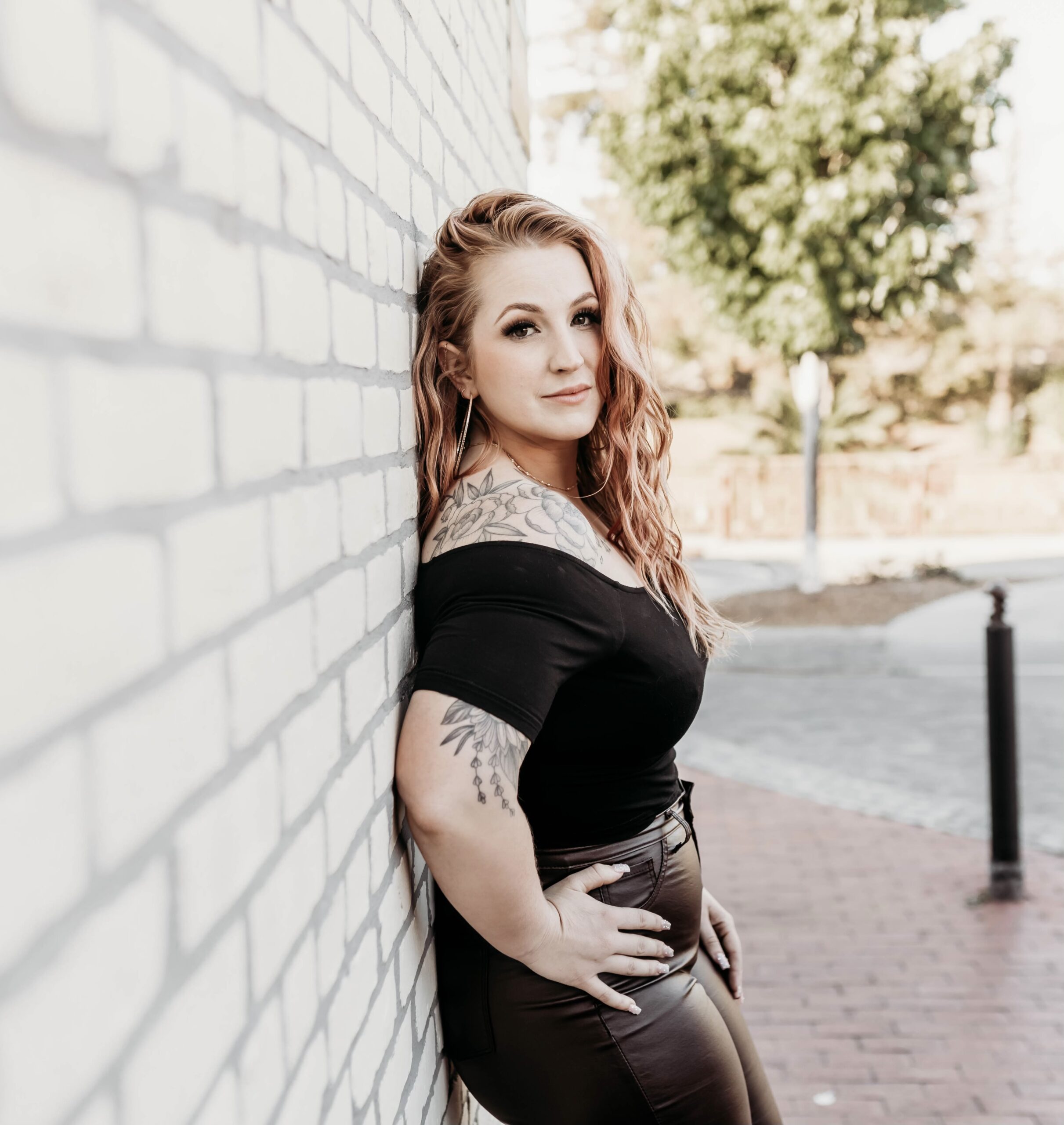 Lydia Carpenter, Co-owner of Curlture Salon stands against a wall showing her fabulous curly hair.